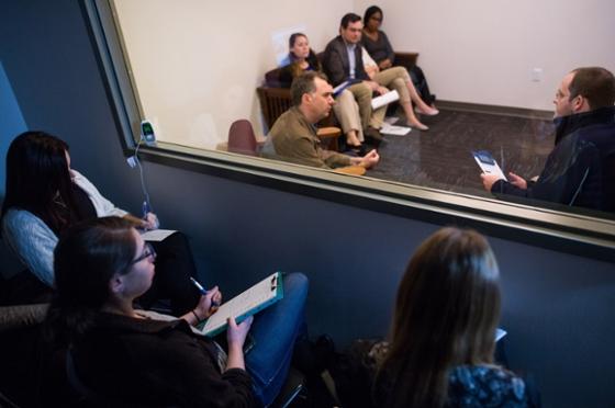 Photo of Chatham University psychology students sitting behind a mirrored window observing a therapy session. 