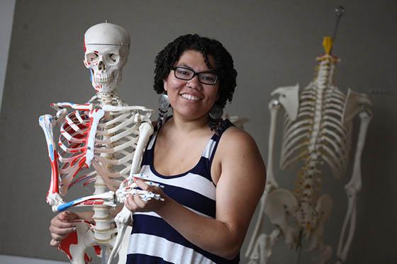 图为一名波胆网站的学生与一个骨骼模型合影