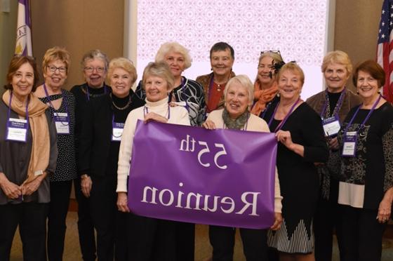 Photo of a group of female Chatham University alumni posing for the camera and holding a purple 55th Reunion flag