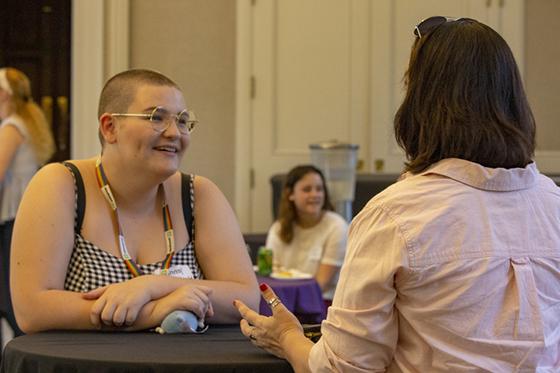 Photo of a middle-aged woman speaking to a young college student at an event
