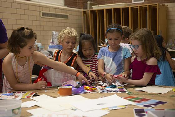 Children gather around a table working on art projects together
